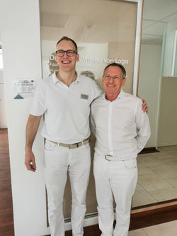 Dr. Axel Weusten und Dr. Winfried von Loga gemeinsam vor dem Praxiseingang.